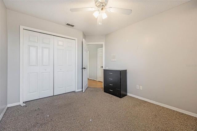 unfurnished bedroom featuring carpet, a textured ceiling, a closet, and ceiling fan