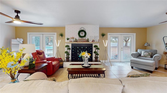 living area featuring baseboards, a ceiling fan, tile patterned flooring, french doors, and a fireplace