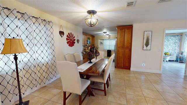 dining area with light tile patterned floors, a textured ceiling, visible vents, baseboards, and an inviting chandelier