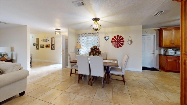 dining area featuring light tile patterned floors, a textured ceiling, and visible vents