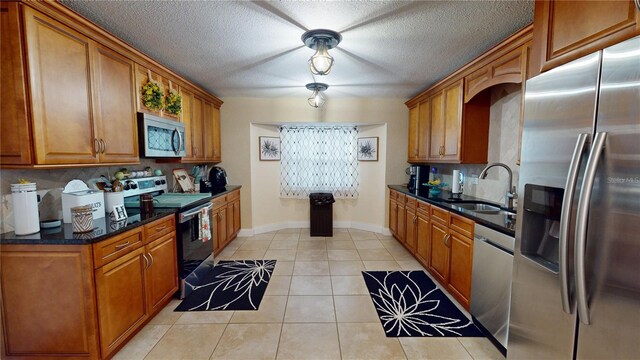 kitchen with light tile patterned floors, stainless steel appliances, a sink, and brown cabinets