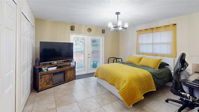 tiled bedroom with a textured ceiling, access to exterior, french doors, a closet, and an inviting chandelier