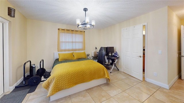 bedroom with a chandelier, light tile patterned floors, a textured ceiling, and baseboards