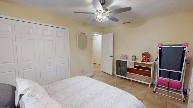 bedroom with baseboards, visible vents, a ceiling fan, a closet, and light tile patterned flooring