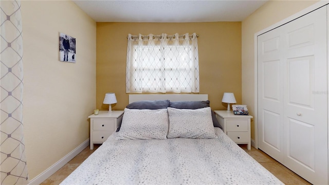 bedroom featuring light tile patterned floors, baseboards, and a closet