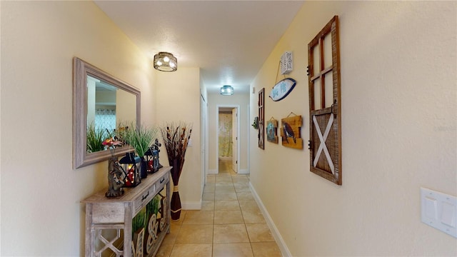 corridor featuring light tile patterned flooring and baseboards