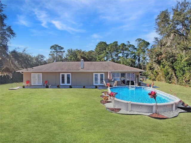 outdoor pool featuring french doors and a yard