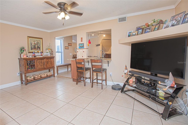 tiled living room with ceiling fan, ornamental molding, and sink