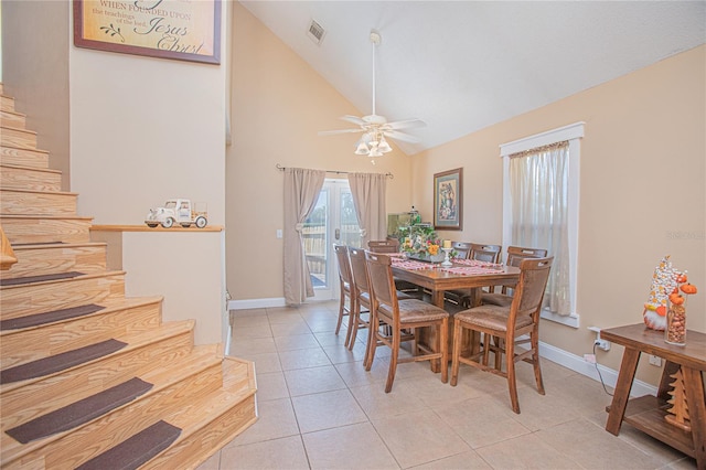 tiled dining space with ceiling fan and high vaulted ceiling