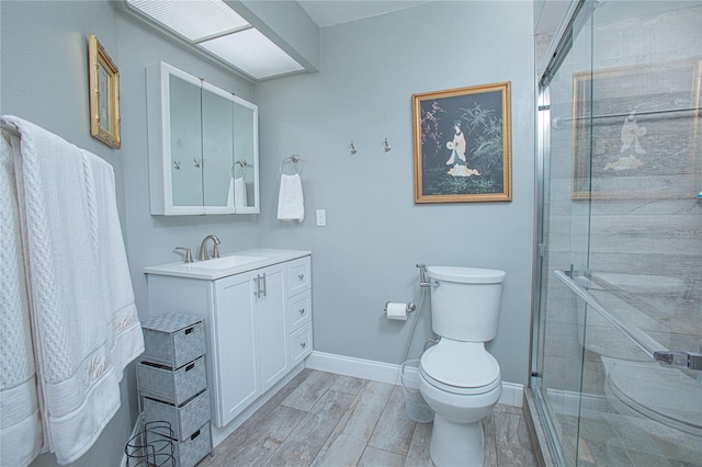 bathroom featuring hardwood / wood-style flooring, vanity, toilet, and walk in shower