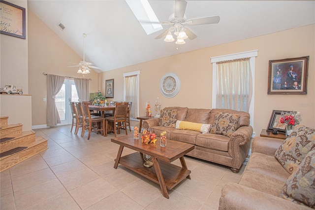 living room with a skylight, high vaulted ceiling, ceiling fan, and light tile patterned flooring