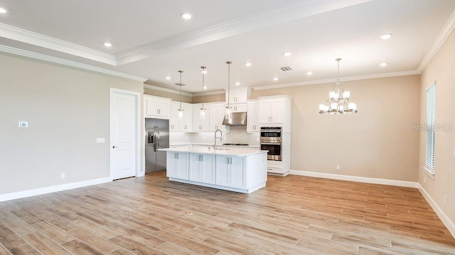 kitchen with stainless steel appliances, crown molding, pendant lighting, light hardwood / wood-style floors, and white cabinets