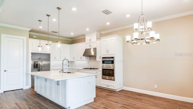 kitchen featuring an island with sink, sink, white cabinets, and pendant lighting