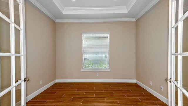 unfurnished room with a tray ceiling, crown molding, and dark hardwood / wood-style floors