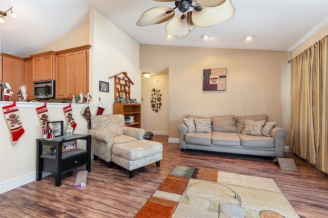 living room with ceiling fan, dark hardwood / wood-style flooring, and vaulted ceiling