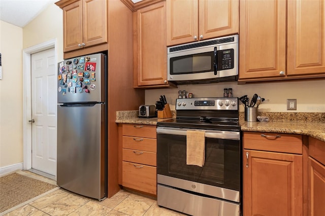 kitchen with light stone counters and appliances with stainless steel finishes