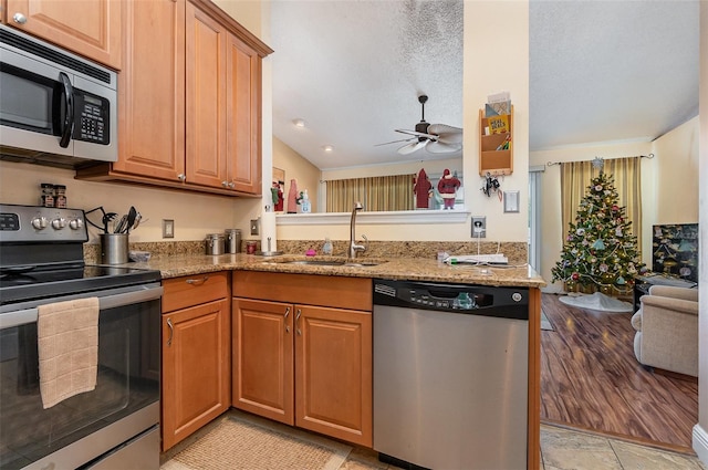 kitchen featuring light stone countertops, stainless steel appliances, ceiling fan, sink, and light hardwood / wood-style flooring