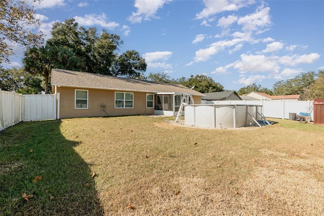 back of property featuring a fenced in pool, a lawn, and a sunroom