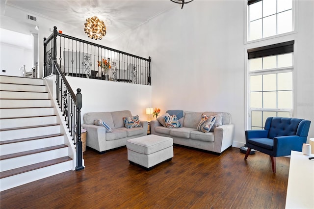 living room featuring a chandelier, a towering ceiling, dark hardwood / wood-style flooring, and ornamental molding