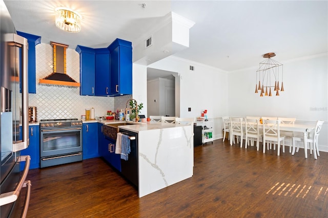 kitchen featuring dark wood-type flooring, blue cabinets, wall chimney exhaust hood, kitchen peninsula, and stainless steel appliances