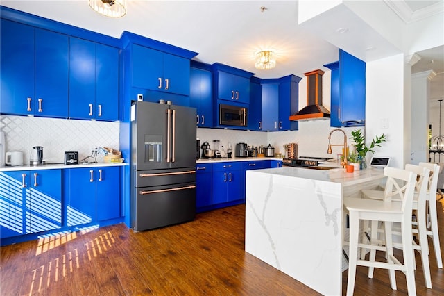 kitchen with wall chimney range hood, ornamental molding, blue cabinetry, dark hardwood / wood-style flooring, and stainless steel appliances