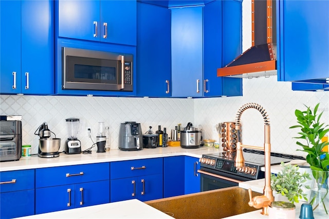 kitchen featuring premium range hood, blue cabinets, and appliances with stainless steel finishes