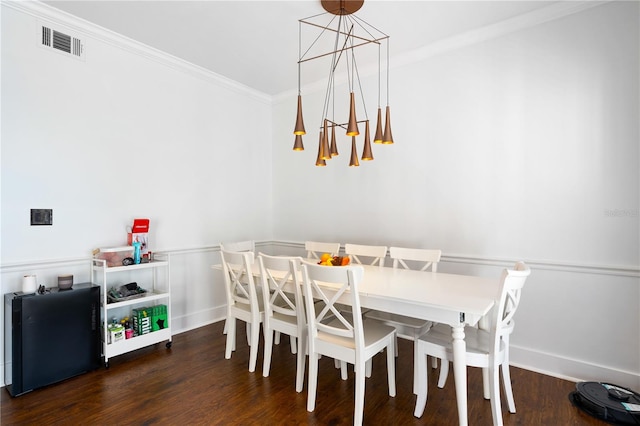 dining area featuring dark hardwood / wood-style floors, ornamental molding, and an inviting chandelier