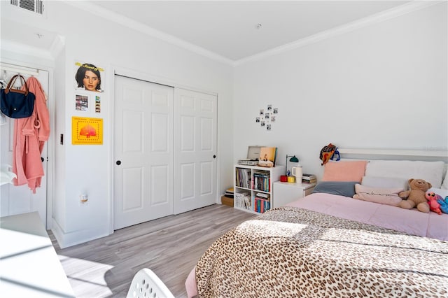 bedroom with a closet, ornamental molding, and light hardwood / wood-style flooring