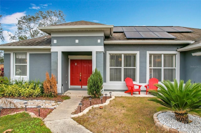 entrance to property with solar panels and a yard