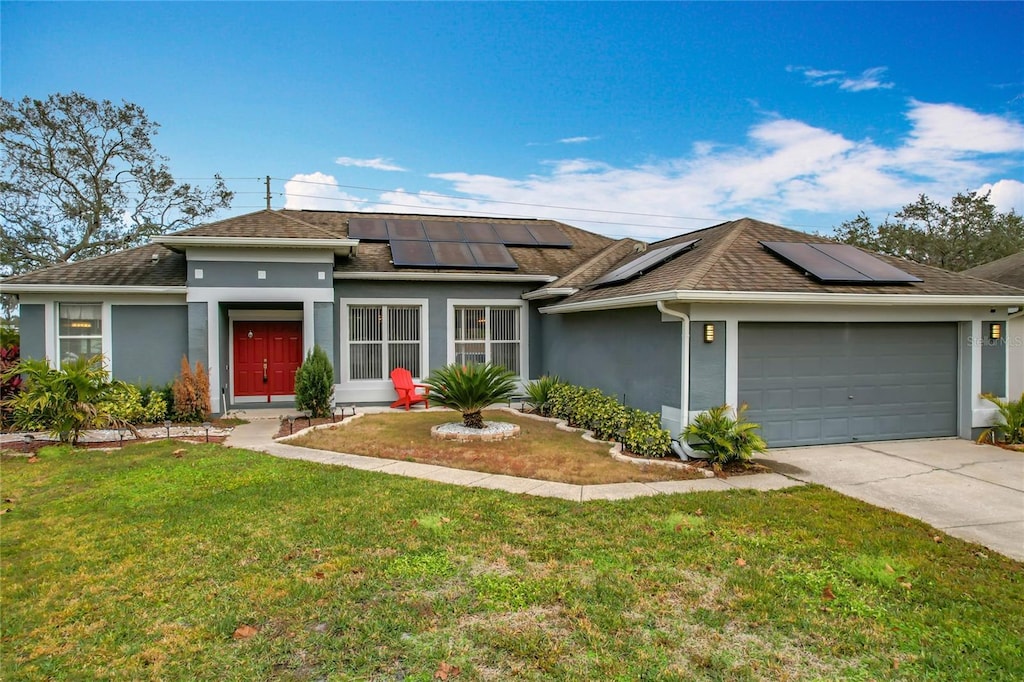 view of front of home with a garage, solar panels, and a front lawn