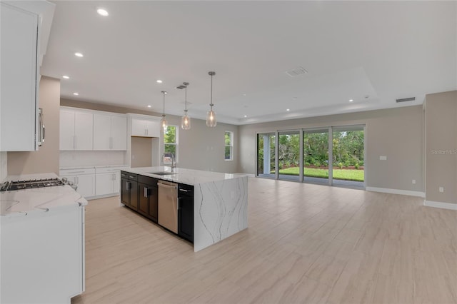 kitchen featuring light stone counters, sink, a center island with sink, light hardwood / wood-style floors, and white cabinetry