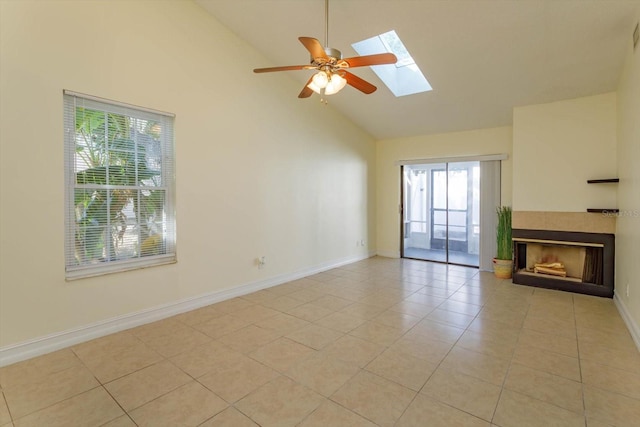 unfurnished living room featuring high vaulted ceiling, a skylight, ceiling fan, light tile patterned floors, and a fireplace