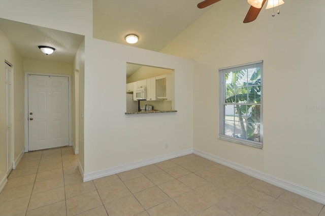 spare room with a textured ceiling, ceiling fan, light tile patterned floors, and lofted ceiling