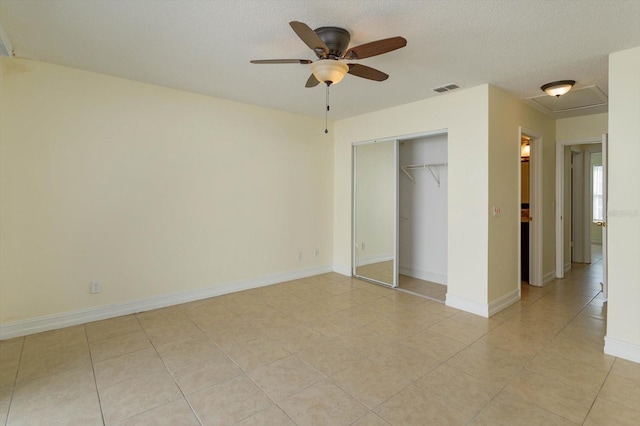 unfurnished bedroom featuring ceiling fan, a closet, light tile patterned flooring, and a textured ceiling