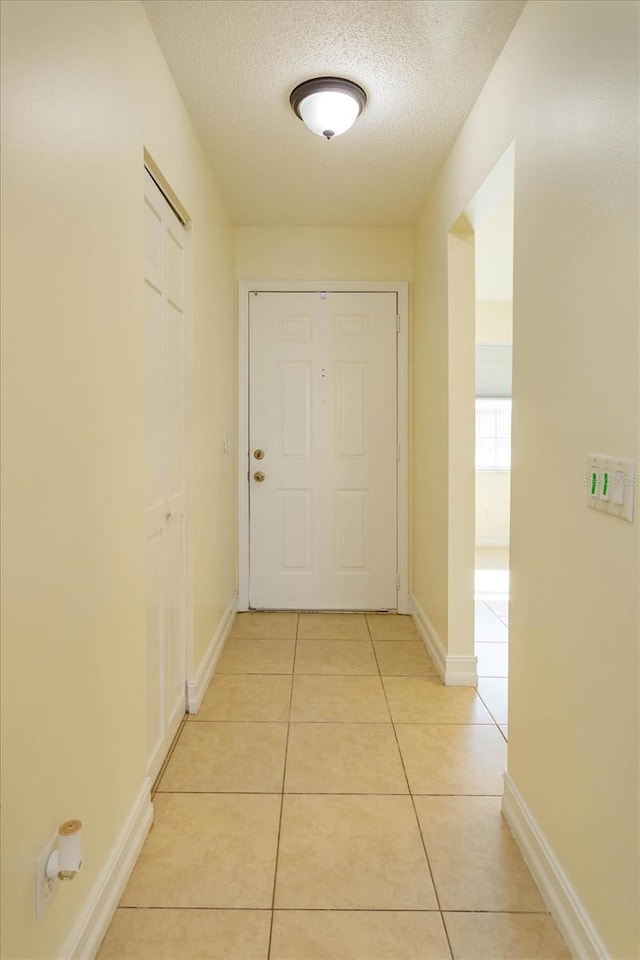 hall featuring light tile patterned floors and a textured ceiling