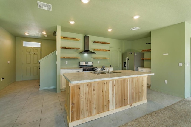 kitchen featuring sink, stainless steel appliances, an island with sink, and wall chimney range hood