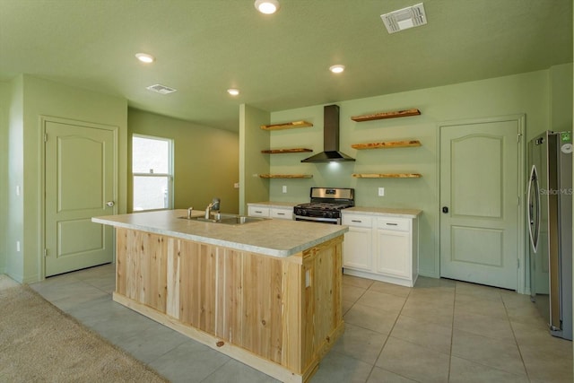 kitchen with stainless steel appliances, sink, wall chimney range hood, light tile patterned floors, and an island with sink