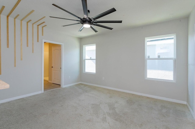 carpeted spare room featuring ceiling fan