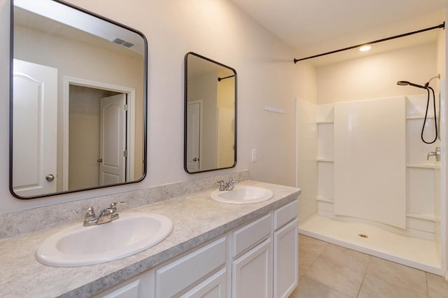 bathroom with tile patterned flooring, vanity, and walk in shower