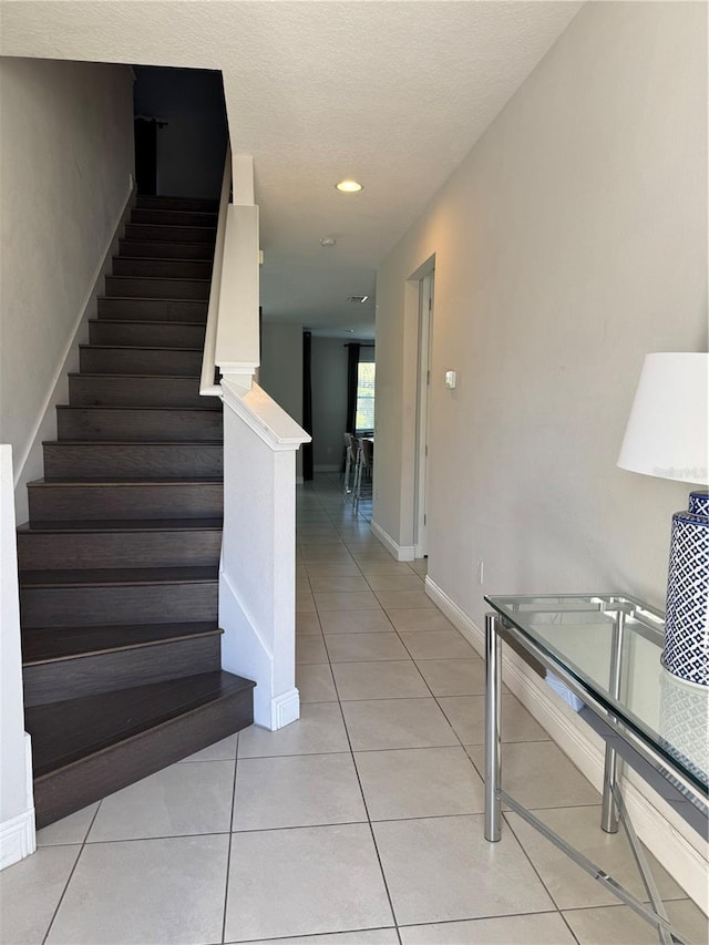 stairs with tile patterned flooring and a textured ceiling