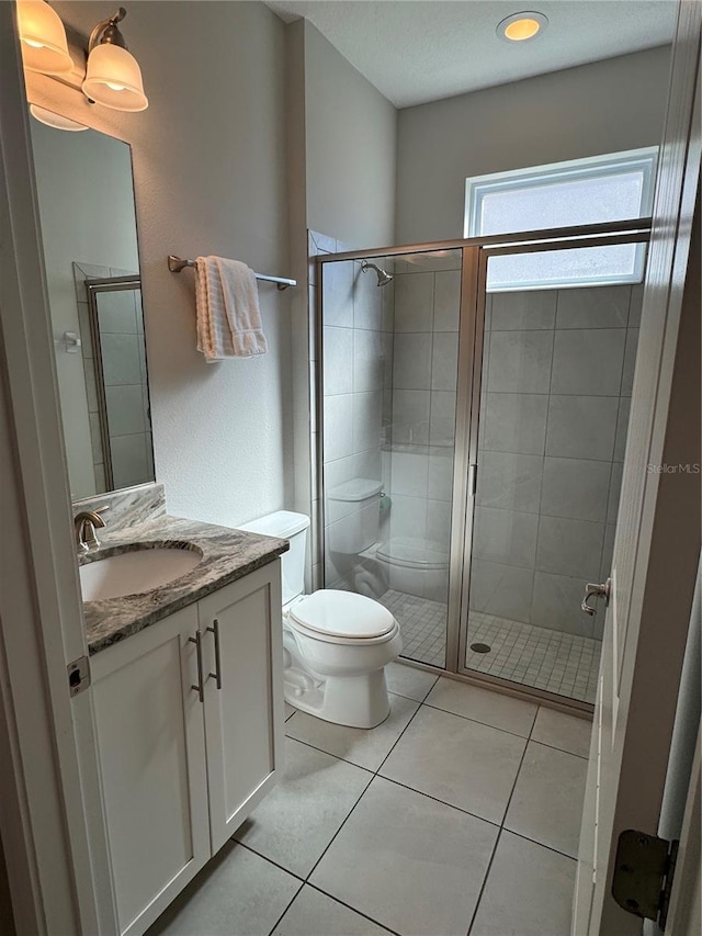 bathroom with toilet, vanity, tile patterned floors, and an enclosed shower