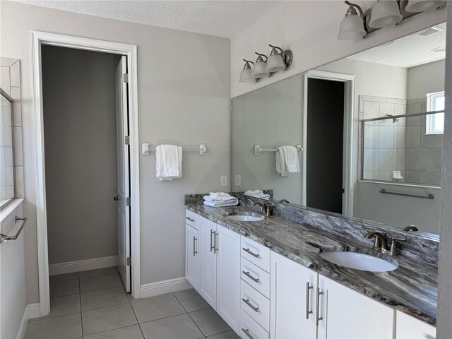 bathroom with tile patterned flooring, vanity, a textured ceiling, and walk in shower