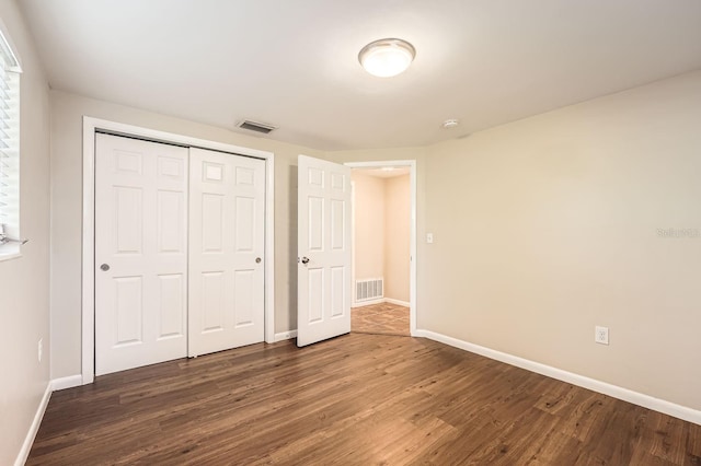 unfurnished bedroom with a closet and dark hardwood / wood-style floors