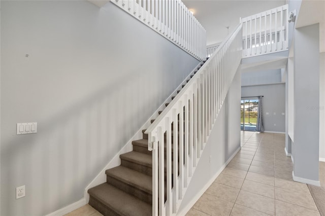 staircase featuring tile patterned floors and a towering ceiling