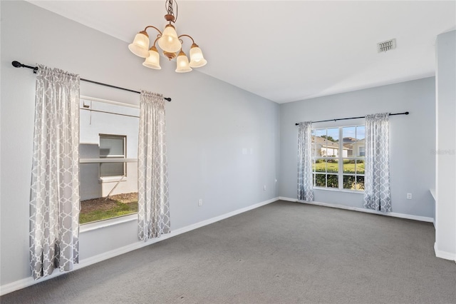 carpeted empty room featuring a chandelier