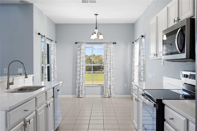 kitchen featuring white cabinetry, sink, hanging light fixtures, light tile patterned floors, and appliances with stainless steel finishes