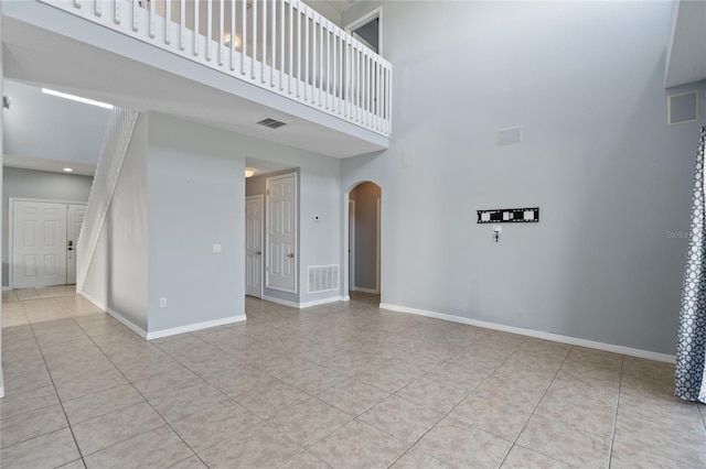 spare room with a high ceiling and light tile patterned flooring