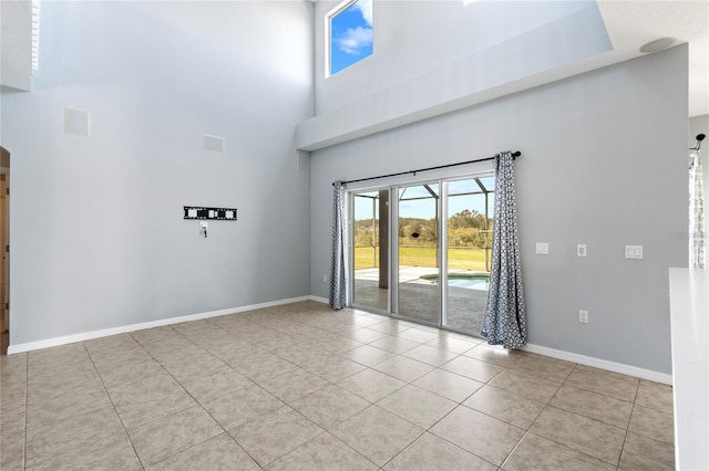 empty room with light tile patterned floors and a high ceiling