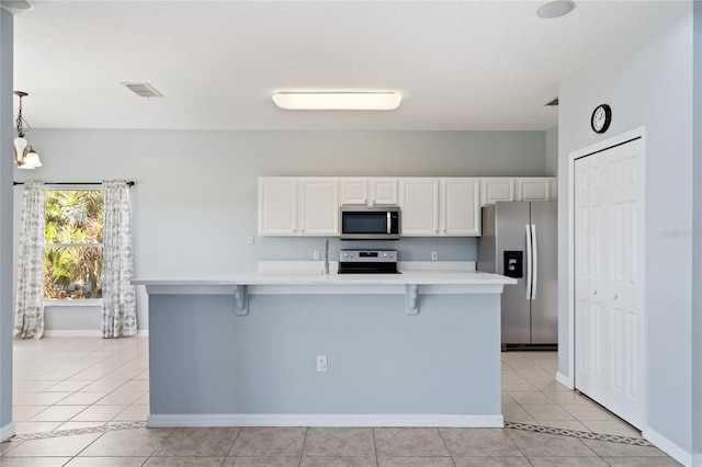 kitchen featuring a breakfast bar, white cabinetry, stainless steel appliances, and hanging light fixtures