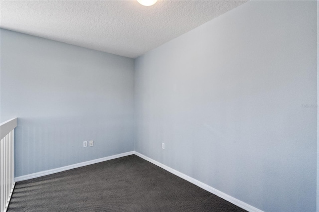 spare room with dark carpet and a textured ceiling